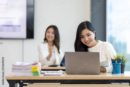 Attractive Asian businesswoman in office working with laptop and documents. © Wasan