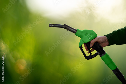 Hand with fuel nozzle with inscription BIO. Carbon neutral bio fuel decarbonization concept photo