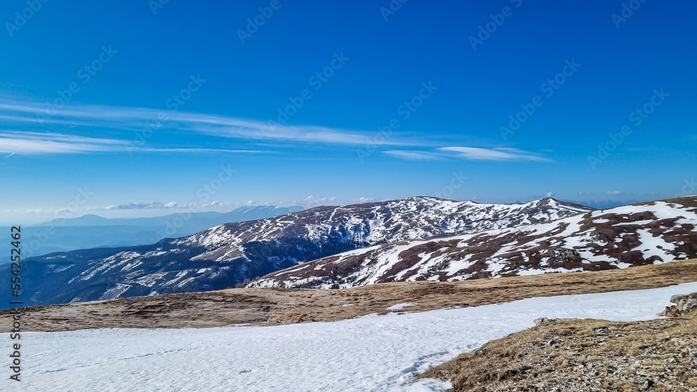 Scenic view on snow covered alpine hills and Karawanks mountains seen from alpine meadow at Ladinger Spitz, Saualpe, Lavanttal Alps, Carinthia, Austria, Europe. Hiking trail in winter in Wolfsberg