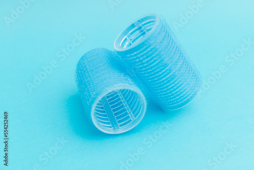 Large hair curlers on blue background, monochrome