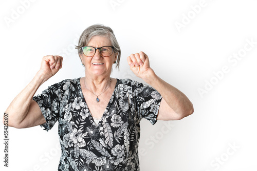 Portrait of senior woman with cheerful expression of victory looking at camera over white background