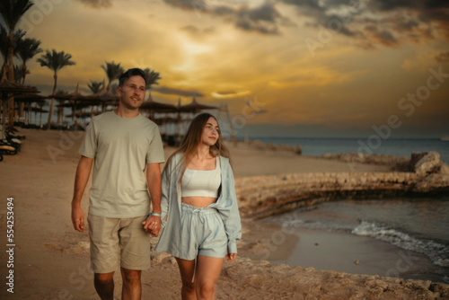 couple in love on the shore of the beach of the sea walks on a date. Young family couple in summer clothes on a honeymoon trip.
