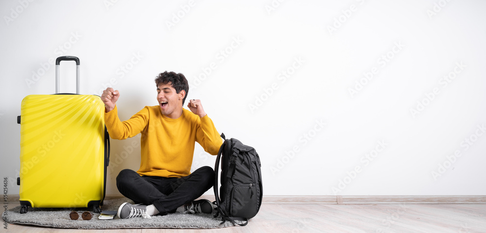 Traveler man with suitcase preparing for air flight dancing with hands sitting on isolated white background. air travel concept Traveler man with suitcase preparing for air flight dancing with hands sitting on isolated white background. air travel concept