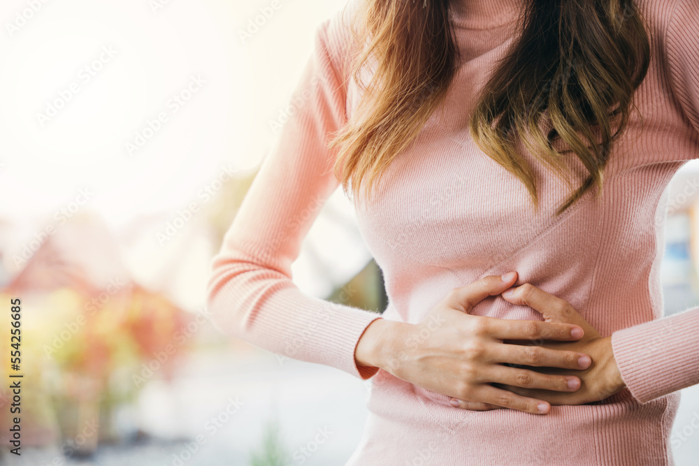 Asian young female suffers from stomachache after eating spoiled food