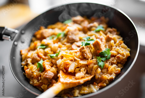 Woman cooking tasty Stew with meat and cabbage in pan on kitchen