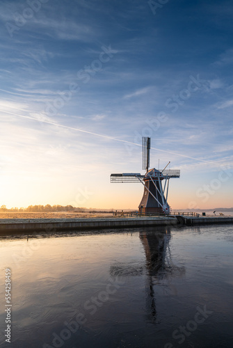 Dutch windmill at a frozen lake on a cold morning in december.