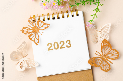Photography A 2023 calendar desk for the organizer to plan and paper butterfly with flower on yellow background