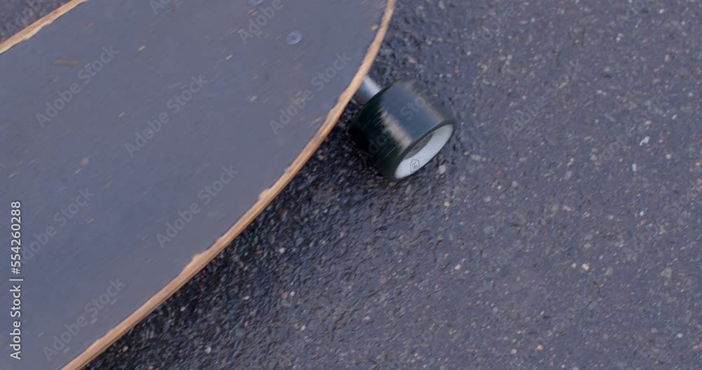 The movement of the longboard with his foot on the sidewalk. Preparing