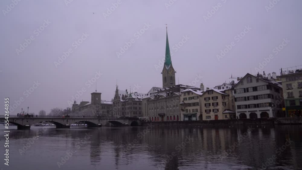 Old town of Zürich with Limmat River and church tower of Women's Minster on a snowy winter day. Movie shot December 16th, 2022, Zurich, Switzerland. Old town of Zürich with Limmat River and church tower of Women's Minster on a snowy winter day. Movie shot December 16th, 2022, Zurich, Switzerland.