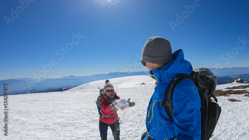Hiking Couple having fun on snow covered alpine meadow at Ladinger Spitz, Saualpe, Lavanttal Alps, Styria Carinthia, Austria, Europe. Woman throwing snow ball in winter. Ski touring, snow shoe tourism