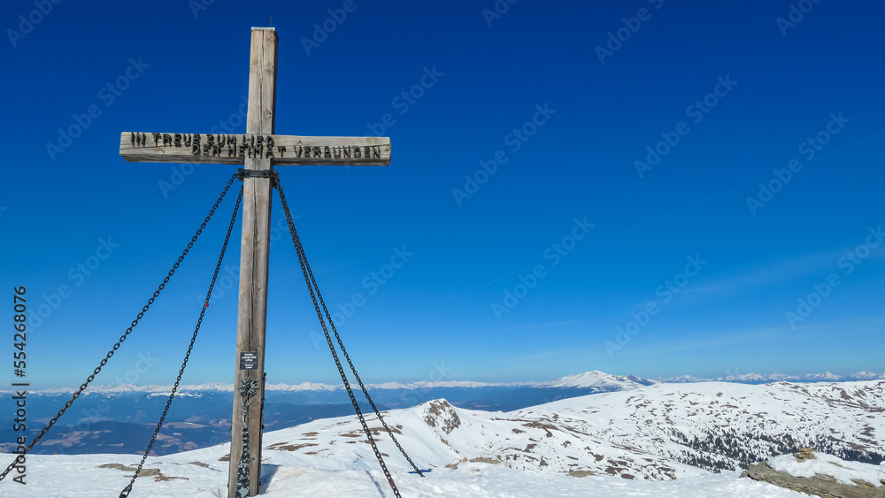 Scenic view from the summit cross of mountain peak Ladinger Spitz, Saualpe, Lavanttal Alps, border Styria Carinthia, Austria, Europe. Hiking trail in Wolfsberg region on sunny winter day. Ski touring Scenic view from the summit cross of mountain peak Ladinger Spitz, Saualpe, Lavanttal Alps, border Styria Carinthia, Austria, Europe. Hiking trail in Wolfsberg region on sunny winter day. Ski touring