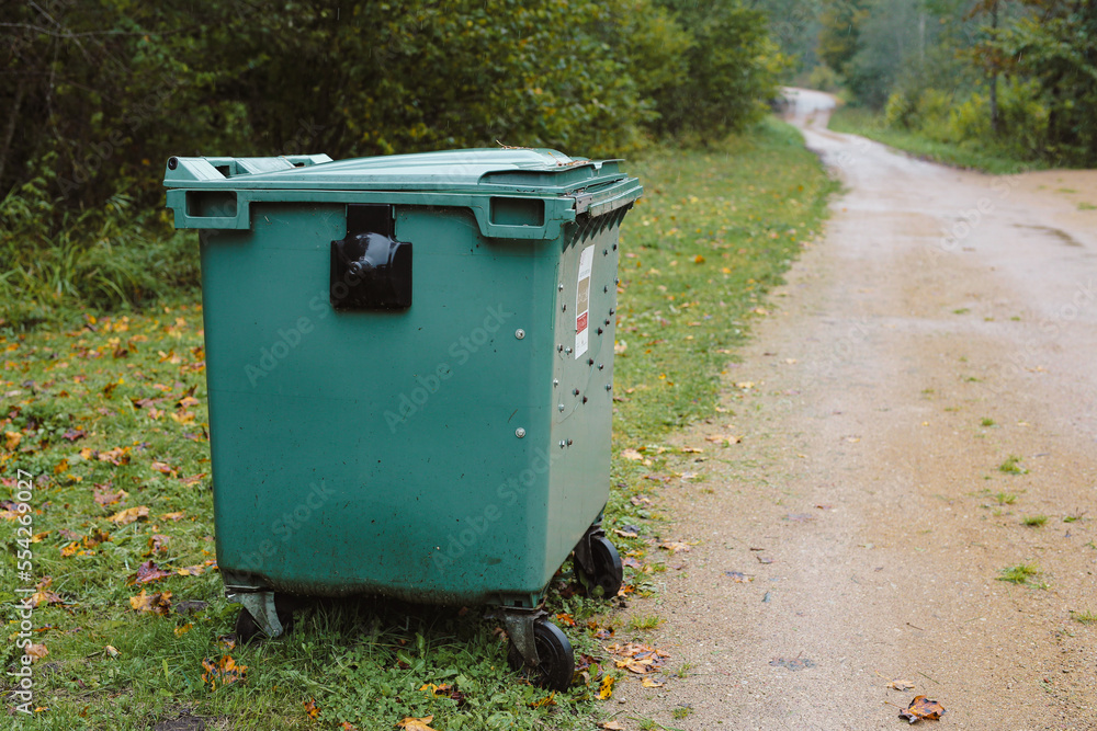 Cyan metal garbage bin on the side of the forest road Cyan metal garbage bin on the side of the forest road