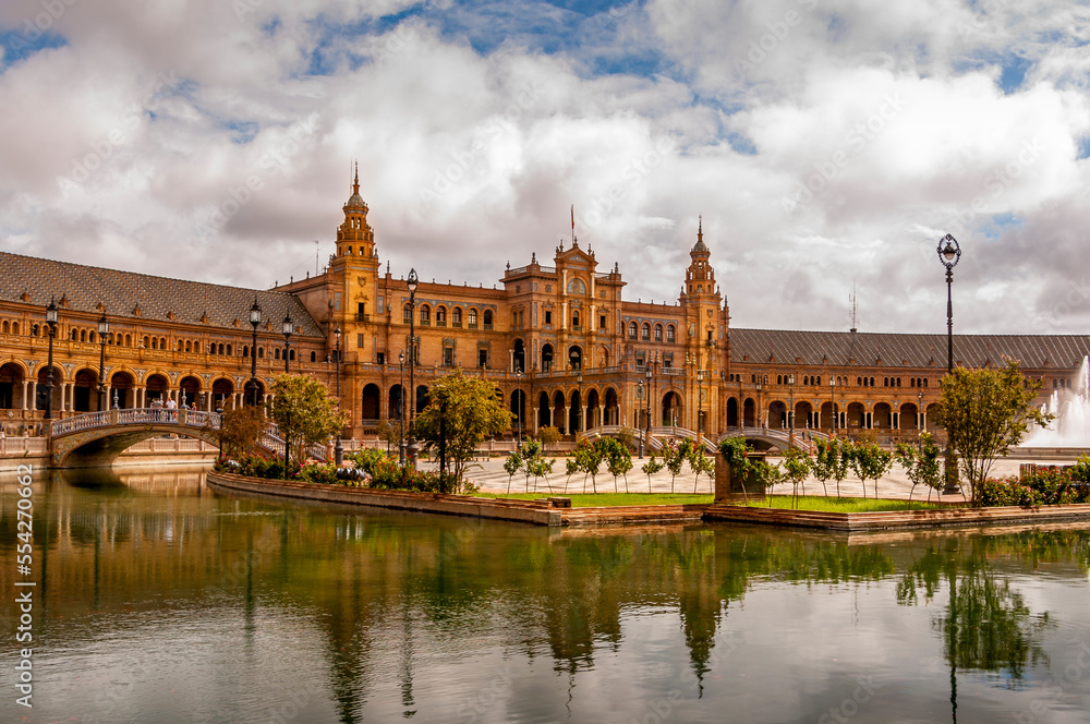 Panorama of the Spain Square Plaza de Espana in Seville, with bridges over the canal, lake, fountain, towers and main entrance to the building. Example of Moorish and Renaissance revival.