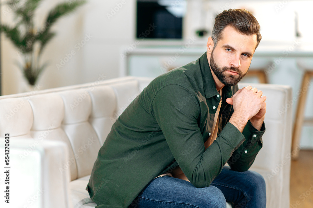 Upset caucasian man, sit on a sofa in living room, looks sadly away, experiencing personal problems, stress, loneliness, needs psychological support and rest. Depression, fatigue, frustration Upset caucasian man, sit on a sofa in living room, looks sadly away, experiencing personal problems, stress, loneliness, needs psychological support and rest. Depression, fatigue, frustration