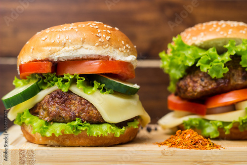Burgers with beef meat, cheese and lettuce, served on cutting board