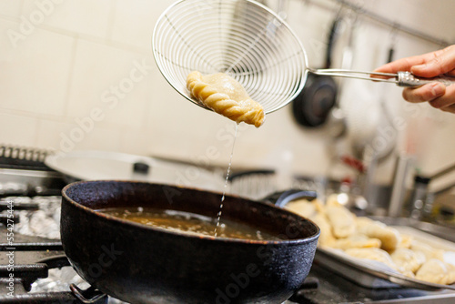 dettaglio della preparazione di ravioli fritti in padella piena d'olio in un cucina tradizionale photo