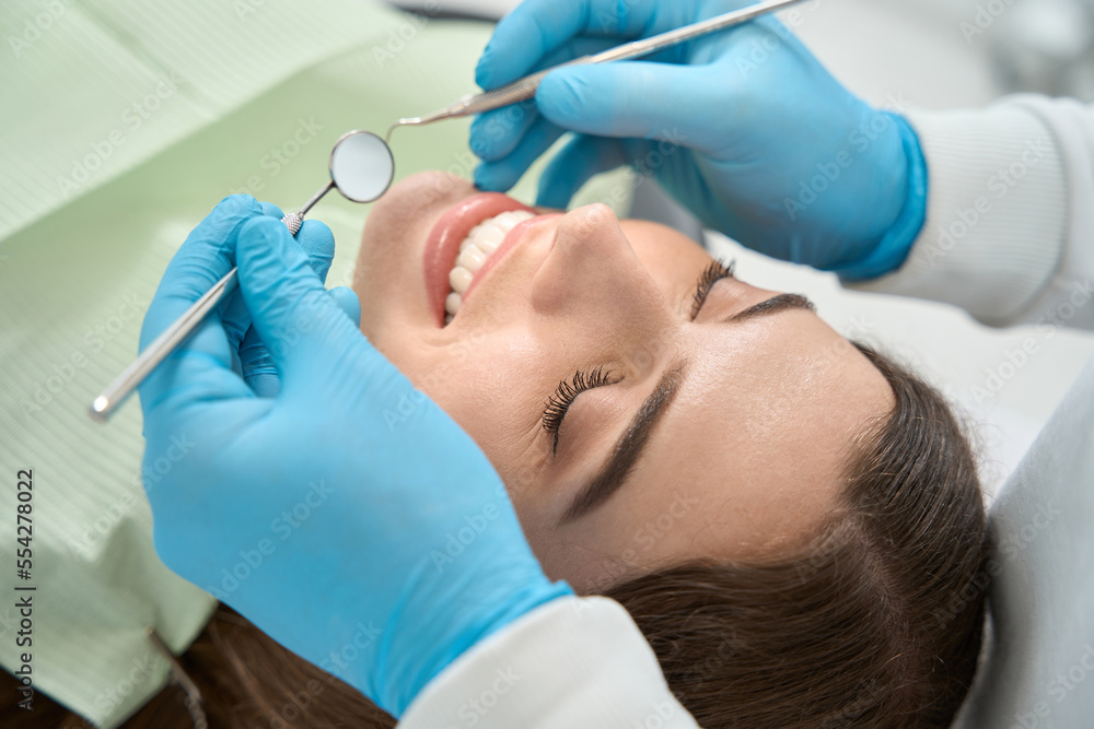 Dentist preparing to examine oral cavity of female client Dentist preparing to examine oral cavity of female client
