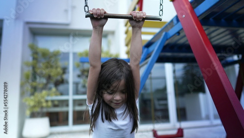 Canvas Print Small girl holding into metal bar at playground child hand holds on monkey bar