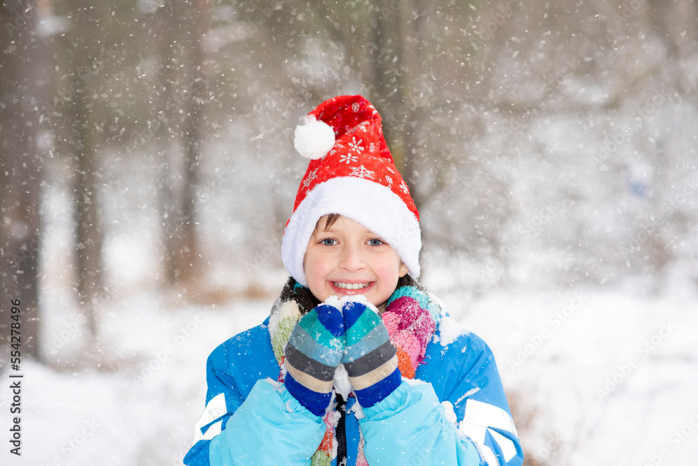 happy child in santa hat in forest holding rummy snow