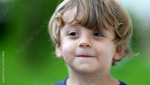 Adorable child portrait smiling at camera little boy face closeup smiles outside at park
