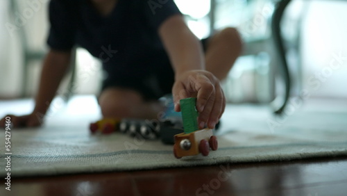 Child plays with traditional car wooden train toy on floor © Marco