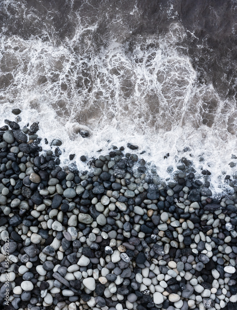 Obraz premium Drohnenaufnahme,Meeresbrandung mit großen runden Steinen am Strand von Rocha da Relva,Insel Sao Miguel,Azoren,Portugal,