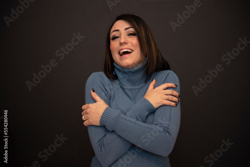 bella ragazza con maglione azzurro su sfondo nero che si abbraccia photo