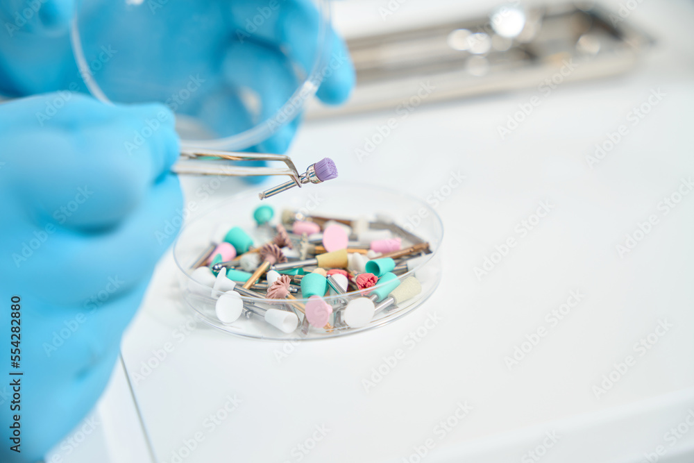 Experienced stomatologist preparing to perform teeth-polishing procedure Experienced stomatologist preparing to perform teeth-polishing procedure