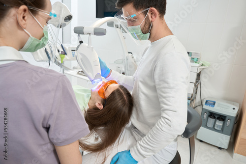 Experienced dentist doing dental procedure on client with modern equipment
