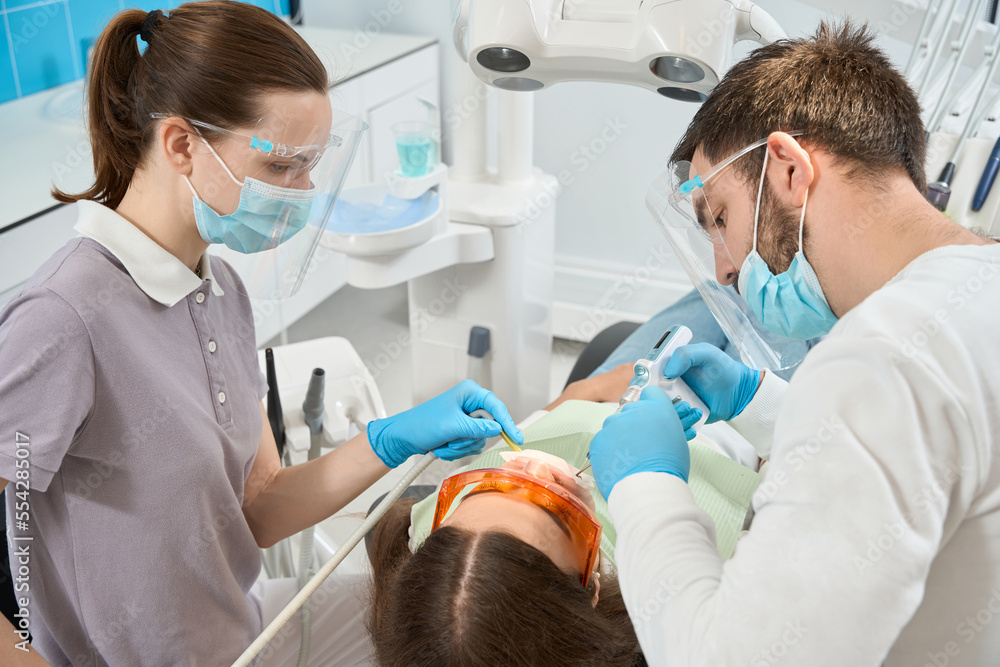 Serious stomatologist numbing female patient mouth before treatment Serious stomatologist numbing female patient mouth before treatment