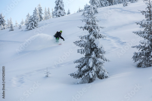 Snowboard freerider in the mountains curved and brakes spraying loose deep snow on the freeride slope