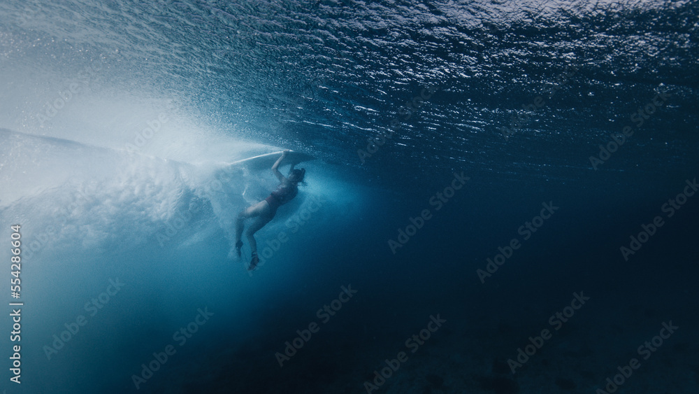Naklejka premium Woman surfer does eskimo roll to pass the ocean wave