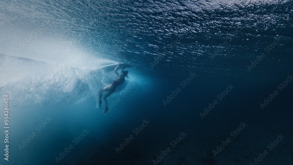 Woman surfer does eskimo roll to pass the ocean wave