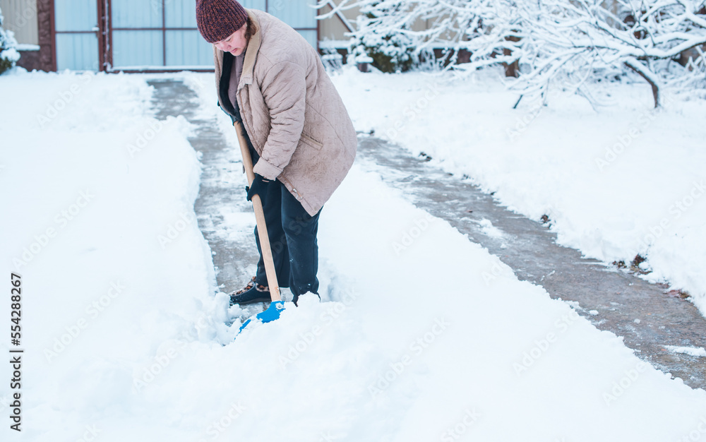 Winter problems concept . Woman digging snow with shovel at yard. Lady standing with blue shovel and cleaning snow .Winter routine concept