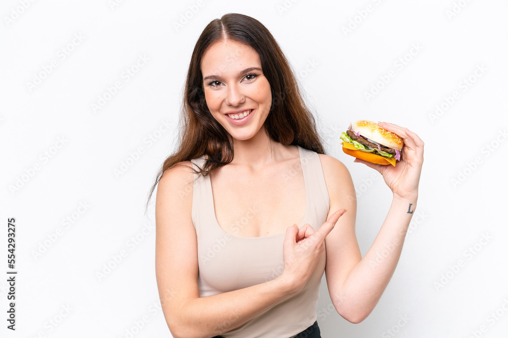 Young caucasian woman holding a burger isolated on white background and pointing it Young caucasian woman holding a burger isolated on white background and pointing it