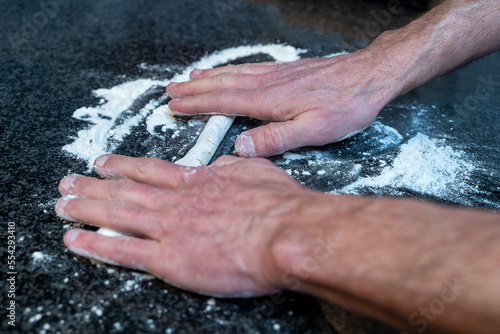 Close-up of male hands making dough for cookies on a granite countertop