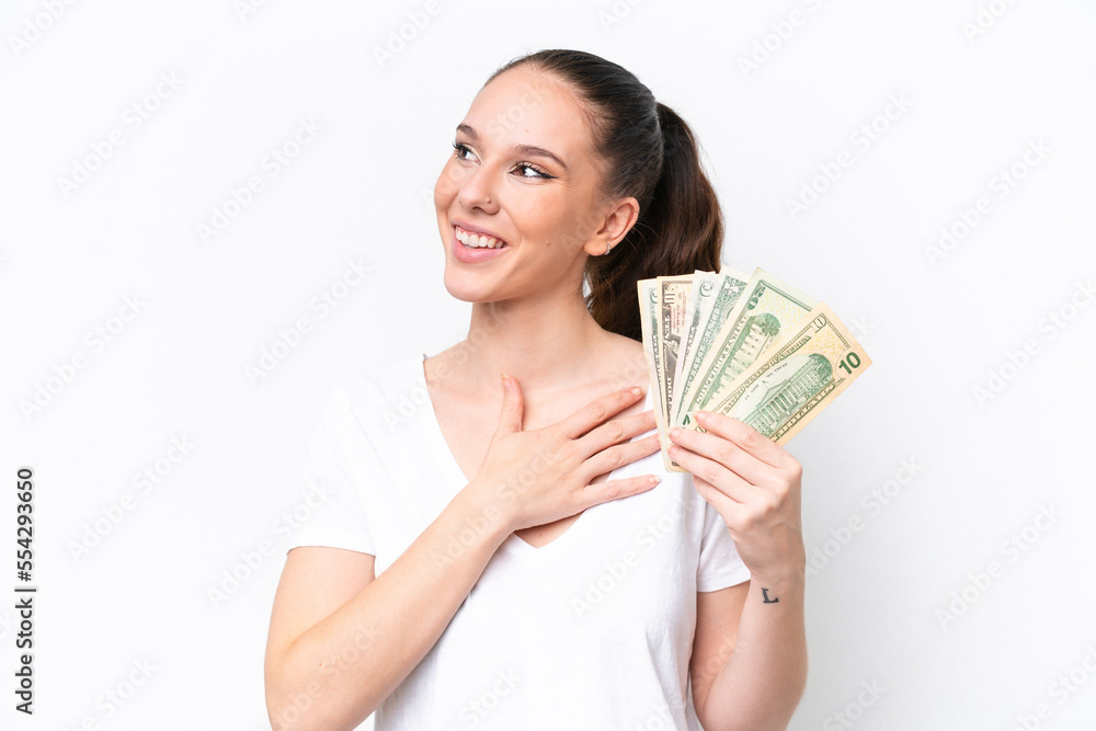 Young caucasian woman taking a lot of money isolated on white background looking up while smiling Young caucasian woman taking a lot of money isolated on white background looking up while smiling