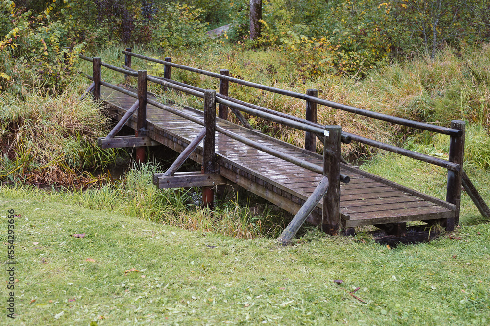 A Rustic brown Wooden Bridge Over a Small river