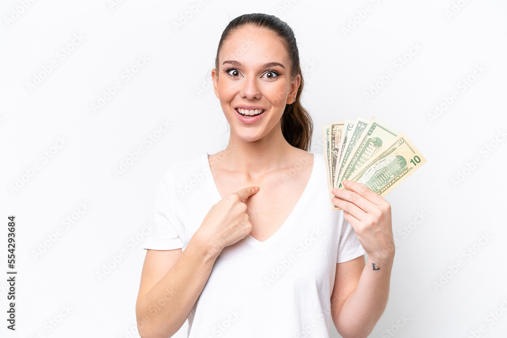 Young caucasian woman taking a lot of money isolated on white background with surprise facial expression Young caucasian woman taking a lot of money isolated on white background with surprise facial expression