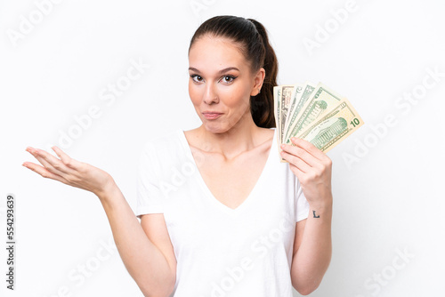 Young caucasian woman taking a lot of money isolated on white background having doubts while raising hands