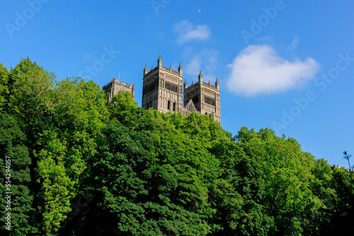 Durham England: 2022-06-07: Durham Cathedral exterior during sunny summer day with lush green trees and blue sky. Closeup view