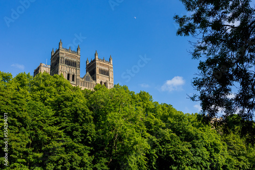 Durham England: 2022-06-07: Durham Cathedral exterior during sunny summer day with lush green trees and blue sky. Closeup view