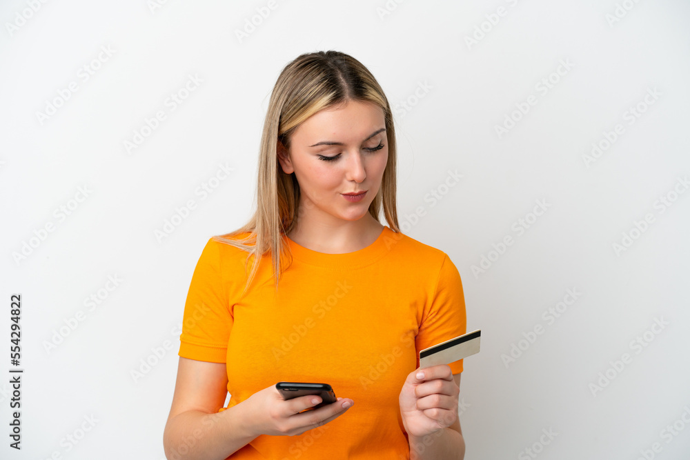 Young caucasian woman isolated on white background buying with the mobile with a credit card Young caucasian woman isolated on white background buying with the mobile with a credit card