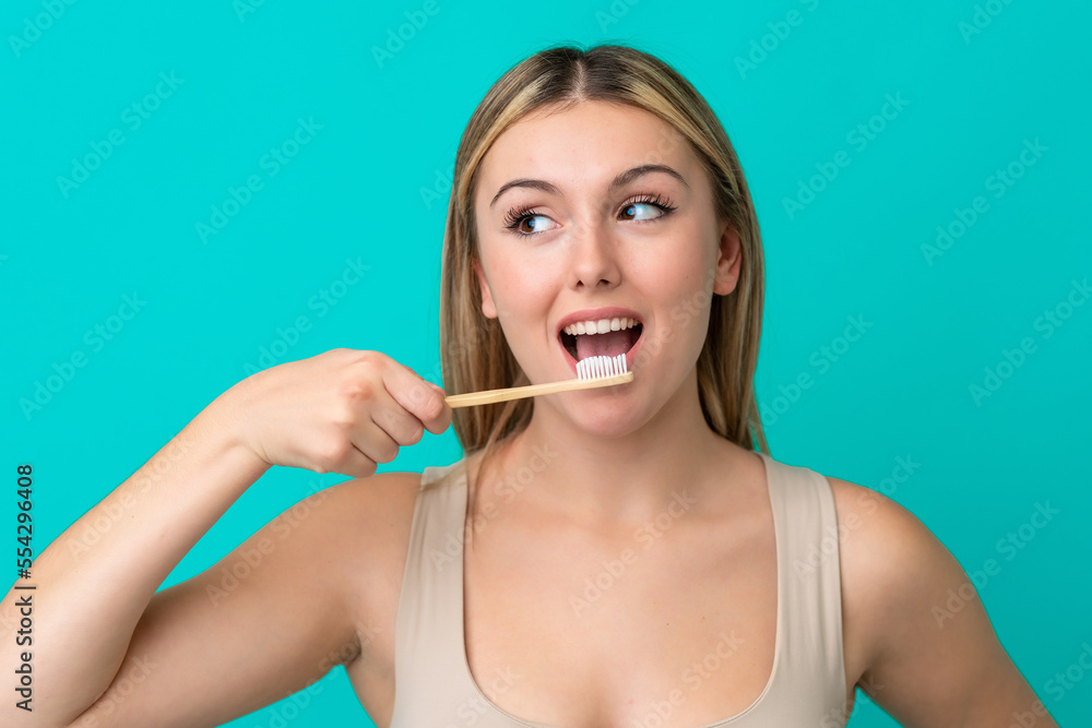 Young caucasian woman isolated on blue background with a toothbrush Young caucasian woman isolated on blue background with a toothbrush