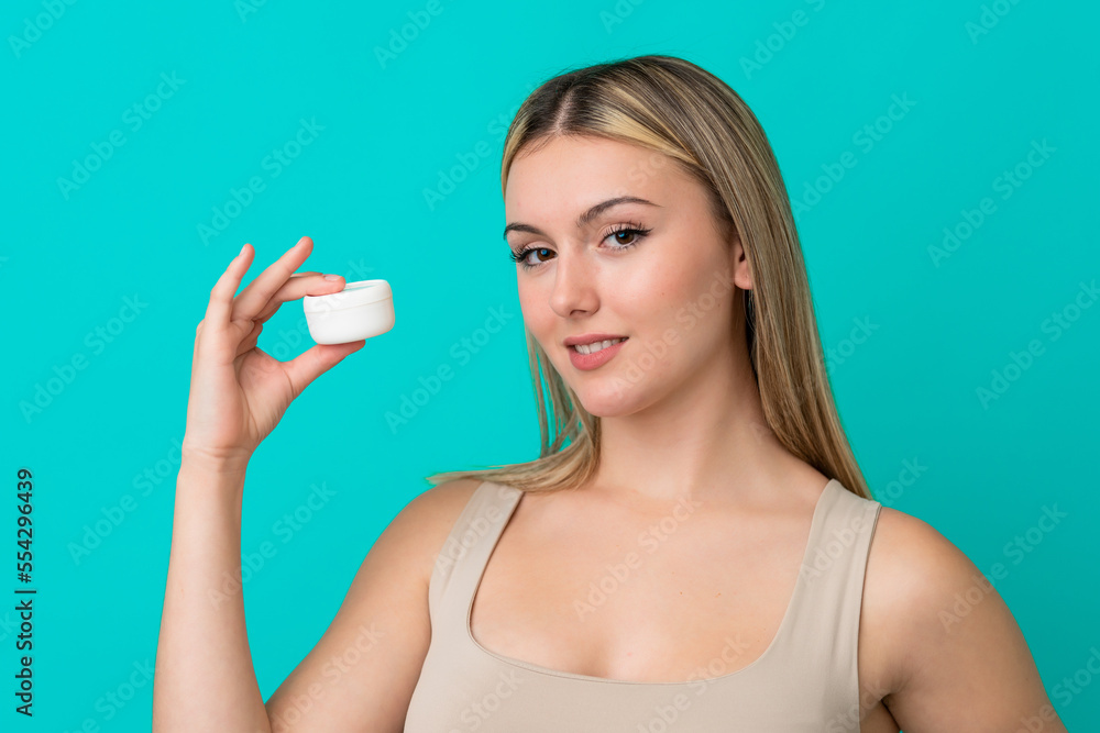Young caucasian woman isolated on blue background with moisturizer Young caucasian woman isolated on blue background with moisturizer