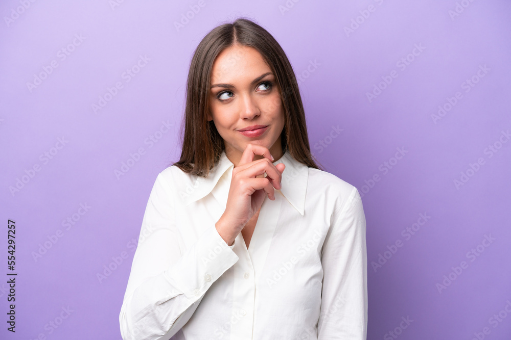 Young caucasian woman isolated on purple background and looking up Young caucasian woman isolated on purple background and looking up