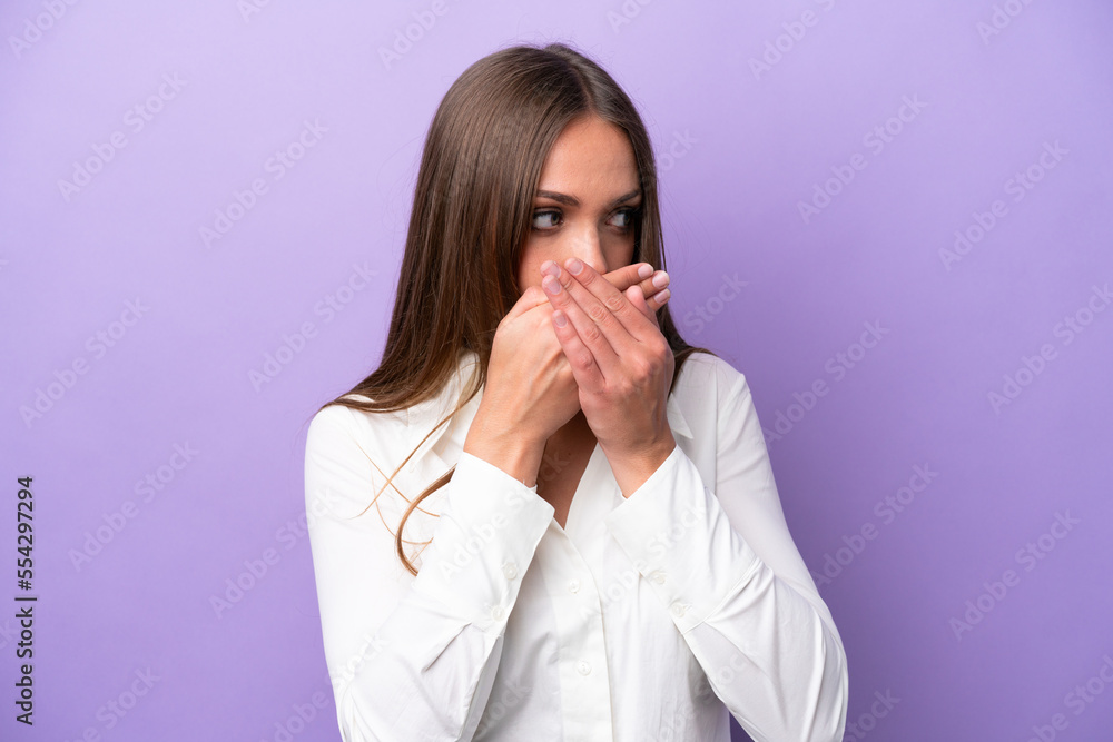 Young caucasian woman isolated on purple background covering mouth and looking to the side Young caucasian woman isolated on purple background covering mouth and looking to the side