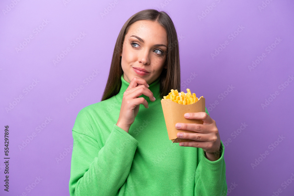Young caucasian woman holding fried chips on purple background and looking up Young caucasian woman holding fried chips on purple background and looking up