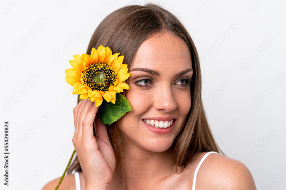 Young caucasian woman isolated on white background holding a sunflower while smiling. Close up portrait