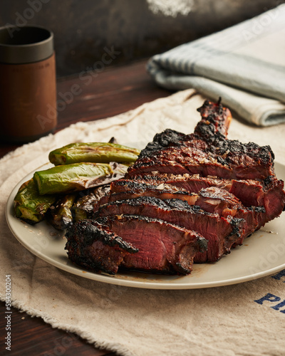 Grilled T-bone steak with charred okra on a ceramic plate.
